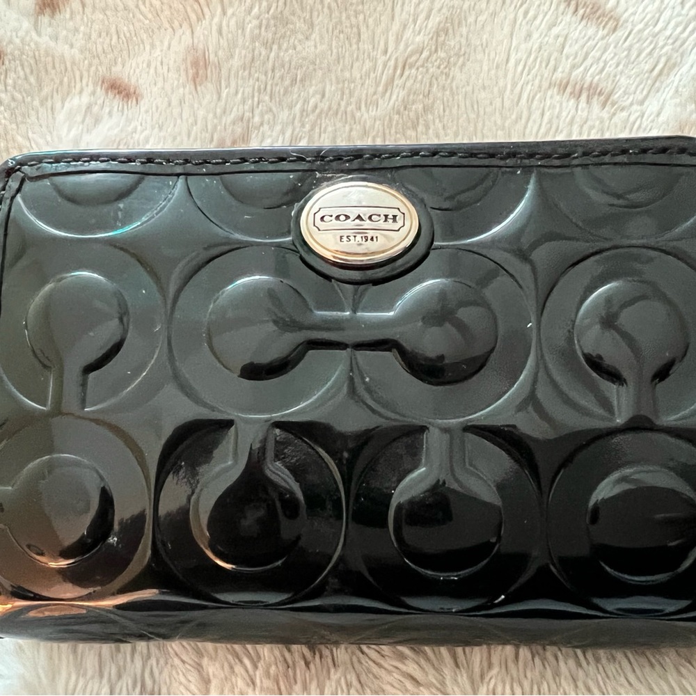 Small black patent leather coach wallet with snap and zipper closure.